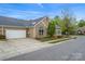 Suburban home with a two-car garage, stone accents, and landscaping, situated on a tree-lined street at 6311 Ridge Path Ln, Charlotte, NC 28269