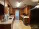 Retro kitchen featuring wooden cabinets, laminate countertop, and a tile floor, connecting to an adjacent living area at 729 Aintree Rd, Charlotte, NC 28215