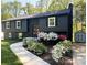 Charming two-story home with dark exterior, landscaped yard, flowering bushes, and a concrete walkway at 7507 Limerick Dr, Charlotte, NC 28270