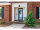 Welcoming brick home entrance with a glass door, wreath, manicured shrub, and black shutters at 8807 Tree Haven Dr, Charlotte, NC 28270
