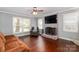Bright living room with hardwood floors, brick fireplace with mounted TV, and views of the backyard at 8807 Tree Haven Dr, Charlotte, NC 28270