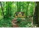 Charming yellow storage shed nestled in a lush green forest, perfect for outdoor storage at 8807 Tree Haven Dr, Charlotte, NC 28270