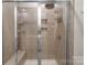 Modern tiled shower with a bench, rainfall showerhead, and shelving for toiletries at 9077 Myrna Dr, Gastonia, NC 28056