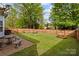 Spacious fenced backyard with a patio, swing, picnic table, and lush green lawn, ideal for relaxation and outdoor enjoyment at 909 Jordans Pond Ln, Charlotte, NC 28214