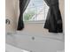 A close-up of a white tub with chrome faucet fixture and dark curtains covering the window at 909 Jordans Pond Ln, Charlotte, NC 28214