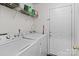 Well-lit laundry room has a washer, dryer, shelving, and access to the front entryway at 909 Jordans Pond Ln, Charlotte, NC 28214