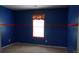 Bedroom with bright blue walls, neutral carpet, window with orange trim, and red decorative border at 9109 Foggy Meadow Rd, Charlotte, NC 28269