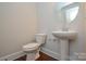 Powder room featuring a pedestal sink, toilet, and wood-look flooring at 10209 Meeting House Nw Dr, Huntersville, NC 28078