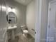 Chic powder room showcasing pedestal sink, toilet and round mirror for a charming space at 1050 Gardenia Dr # 3, Mt Ulla, NC 28125