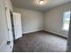 Neutral-toned bedroom featuring soft carpeting, a large window, and a door leading to the hallway at 1050 Gardenia Dr # 3, Mt Ulla, NC 28125
