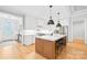 Bright kitchen features white cabinets, stainless appliances, central island with breakfast bar, and hardwood floors at 108 Castleview Ln, Mooresville, NC 28115