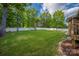Spacious, level backyard with lush green grass, mature trees, and a white fence at 15024 Old Vermillion Dr, Huntersville, NC 28078