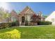 Charming home with a brick and stone facade, lush green lawn, and manicured landscaping at 15024 Old Vermillion Dr, Huntersville, NC 28078