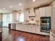 Bright kitchen boasts stainless appliances, granite counters, white cabinetry, and hardwood floors at 15323 Barnsbury Dr, Huntersville, NC 28078