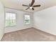 Bright bedroom featuring neutral carpeting, two windows, and a ceiling fan at 15747 Reynolds Dr, Indian Land, SC 29707