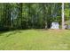 View of a large, grassy backyard with mature trees and a storage shed in the distance, perfect for outdoor activities at 1730 Deer St, Charlotte, NC 28214