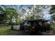Backside view of a cozy house with a fenced-in porch and is nestled among mature trees, with a small storage shed at 2118 Polkville Rd, Shelby, NC 28150