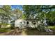 Cozy single story home with white siding and a small porch surrounded by lush greenery and flowers at 2118 Polkville Rd, Shelby, NC 28150