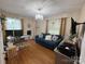 Cozy living room with hardwood floors, a blue sofa, modern chandelier, and a functional workstation area at 212 E Stewart Ave, Mooresville, NC 28115