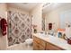Bathroom with a vanity with light wood cabinets features a shower and patterned shower curtain at 215 Raleigh Nw St, Concord, NC 28027