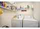 A laundry room has white washer and dryer units with shelving stocked with cleaning supplies at 215 Raleigh Nw St, Concord, NC 28027