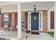 Inviting front porch with brick columns, seating, a decorative wreath, and fresh landscaping at 2856 Huckleberry Hill Dr, Fort Mill, SC 29715