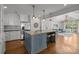 Open-concept kitchen with island, pendant lighting, white cabinets, stainless appliances, and hardwood floors, flows to living room at 3019 Sunset Dr, Charlotte, NC 28209