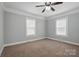 A light-filled bedroom features neutral paint, carpet flooring, a ceiling fan, and two windows at 313 Mayflower Ave, Cramerton, NC 28032