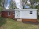 A charming home with a brick facade and white accent siding, set in a grassy yard with mature trees and landscaping at 430 Coolidge Ave, Statesville, NC 28677