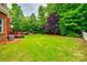 Spacious backyard with mature trees, lush green grass, a deck, and a stone firepit area at 4711 Pearmain Dr, Waxhaw, NC 28173