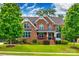 Traditional two-story brick home featuring a landscaped lawn, covered front porch, and mature trees at 4711 Pearmain Dr, Waxhaw, NC 28173