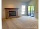 Cozy living room featuring a brick fireplace, neutral carpeting, and sliding glass doors to an outdoor balcony at 5810 Harris Grove Ln, Charlotte, NC 28212