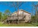 Home's rear exterior features a wooden deck and stairs, set against a backdrop of lush greenery and blue sky at 5944 Freedom Dr, Charlotte, NC 28214