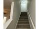 Carpeted staircase with a white handrail and neutral walls at 8829 Michaw Ct, Charlotte, NC 28269