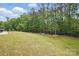 A spacious, green backyard with mature trees and a black metal fence bordering the property at 8923 Happiness Rd, Harrisburg, NC 28075
