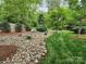 Spacious backyard featuring a rock garden, green grass, trees, and tasteful landscaping at 915 Houston Dr, Monroe, NC 28110