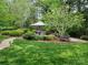 Landscaped backyard with a gazebo, a stone bench, manicured shrubs, and a walkway at 915 Houston Dr, Monroe, NC 28110