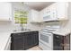 Efficiently designed kitchen with white appliances, dark lower cabinets, and a bright window offering a pleasant view at 9419 Isaac Hunter Dr, Charlotte, NC 28214