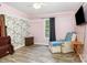 Bedroom featuring pink walls, ceiling fan, hardwood floors, and a cozy chair for relaxation at 103 Woodwinds St, Locust, NC 28097
