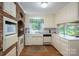View of the kitchen featuring white cabinets and appliances, exposed brick, and a view of nature through the window at 1058 General Hoke Dr, Lincolnton, NC 28092