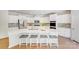 Modern white kitchen features a large center island with gray upholstered stools and stainless steel appliances at 11215 Dappled Light Trl, Charlotte, NC 28227