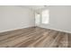 Bright living room featuring wood-look flooring, a window with blinds, and a door to the outside at 1203 Maple Shade Ln, Charlotte, NC 28270