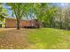 Backyard with brick house, deck, chainlink fence, and tree shaded lawn at 1204 Meadowood Dr, Shelby, NC 28150