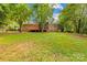 Tree shaded backyard with a brick house, deck, and swing set at 1204 Meadowood Dr, Shelby, NC 28150