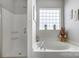 Well-lit bathroom featuring a separate shower, soaking tub, and a glass block window at 13610 Aldenbrook Dr, Huntersville, NC 28078