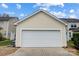 Attached two-car garage with a white door and tan siding at 13610 Aldenbrook Dr, Huntersville, NC 28078
