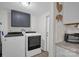 Laundry room with gray cabinets, mosaic backsplash, granite countertops, and modern Whirlpool washer and dryer at 151 Brown Farms Dr, Cleveland, NC 27013