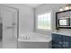 Bright bathroom with a large tub, a separate shower, a modern vanity, and a window at 1614 Crestgate Dr, Waxhaw, NC 28173
