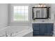 This bathroom features a soaking tub, a large window, and a vanity with a framed mirror at 1614 Crestgate Dr, Waxhaw, NC 28173