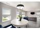 Open-concept dining area with a white round table, blue chairs, modern chandelier, and view into the living space at 1911 Almond Hills Dr, Charlotte, NC 28262